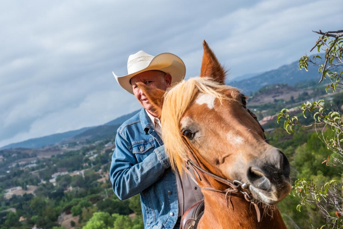 Rider resting with their horse on a hillside trail after a climb, watching how to measure horse recovery